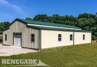 tan steel metal building barn with green roof gutters and down spouts, large door, windows