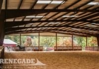 Inside view of steel covered horse riding arena with skylights and partial walls on ends
