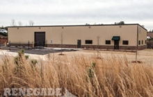 tan steel building with brown trim, brick wainscot, roll up doors, office and warehouse