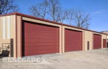 Commercial steel building with large roll up doors, tan with red trim