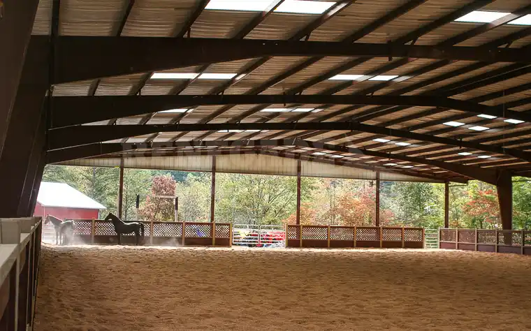 Renegade steel building riding arena interior with horses and fencing