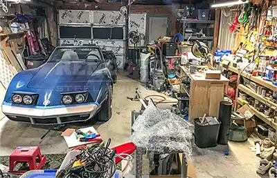 Messy cluttered up garage with Corvette and tools needs a Renegade steel building