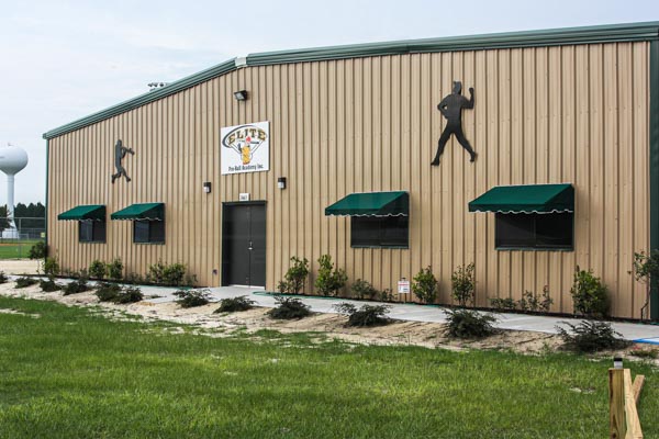 Steel building sports facility with batting cages. Tan walls with green trim.