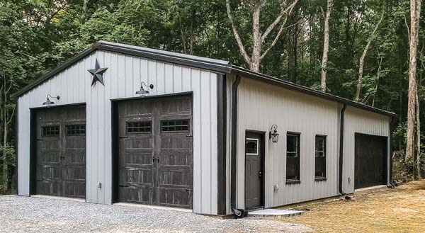 30x50 metal building with light colored walls and dark trim along with rustic panel garage doors.
